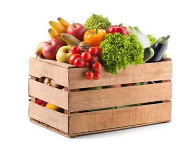 Fruits and vegetables in a wooden crate on white background.